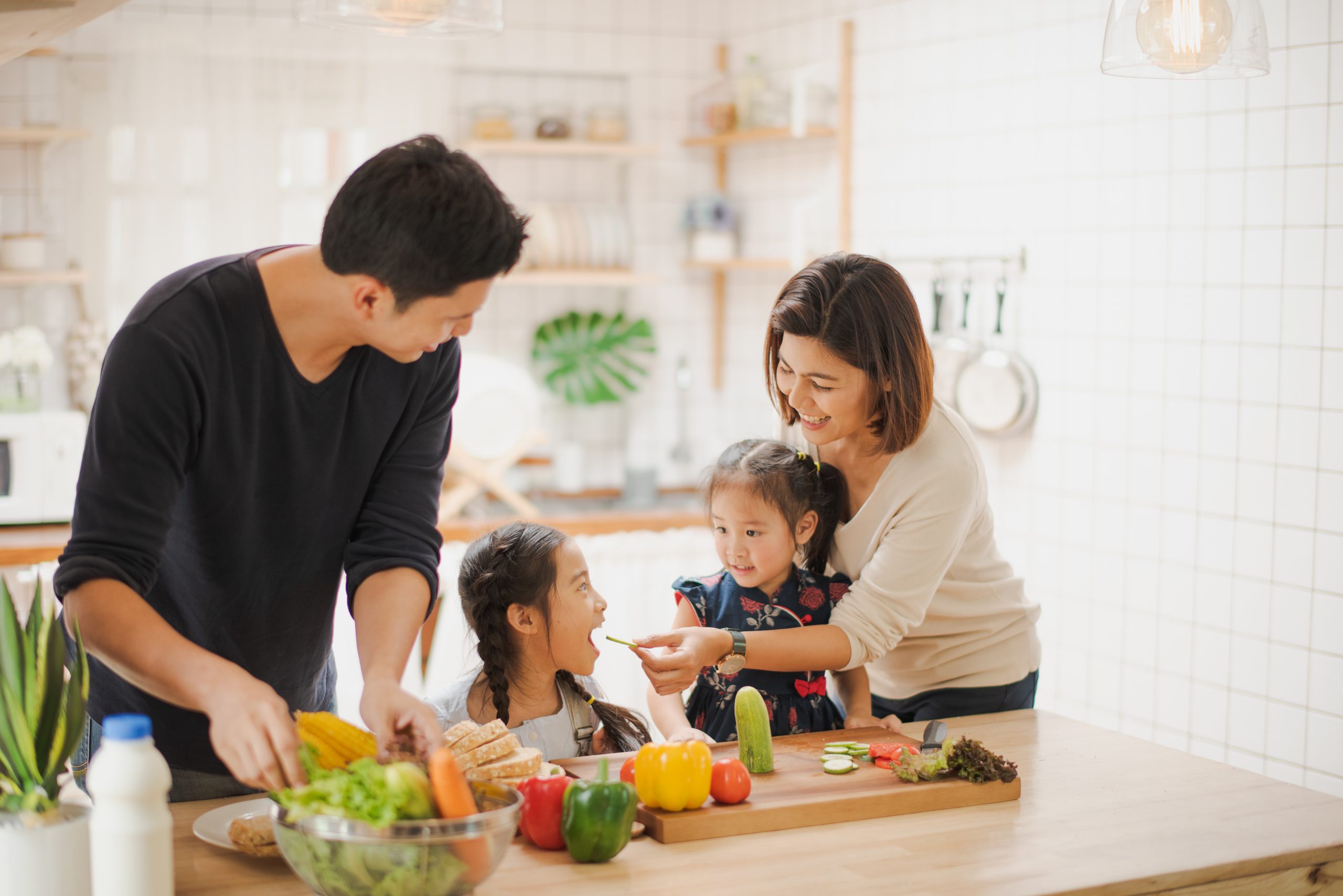 Young Asian love family are preparing the breakfast, sandwich vegetable on table in the kitchen which Excited smiling and felling happy. parent teach daughter to cooking food on the day at home.